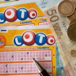Ausgefüllter Lottoschein mit Geldscheinen und Münzen