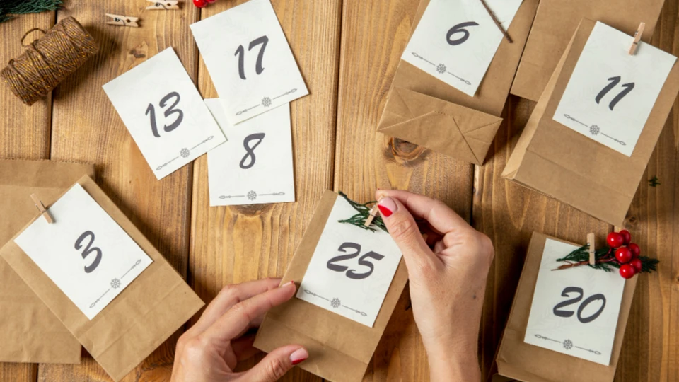 Selbst gebastelter Adventskalender aus Papiertüten mit Zahlen auf Holztisch