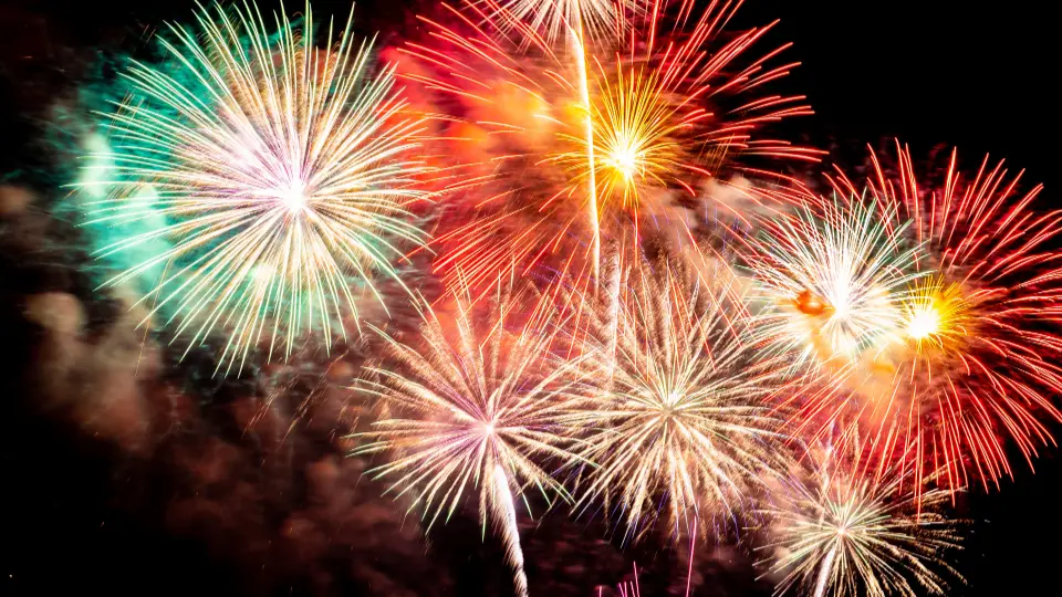 Buntes Silvesterfeuerwerk mit mehreren farbigen Explosionen am Nachthimmel