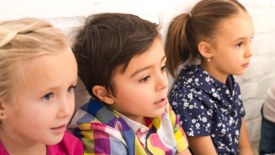 Drei Grundschulkinder schauen neugierig und aufmerksam in die gleiche Richtung