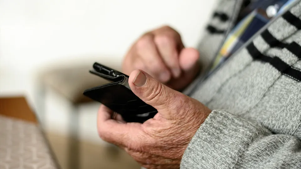 Ältere Hand hält ein Smartphone als Symbol für Seniorennutzung digitaler Geräte